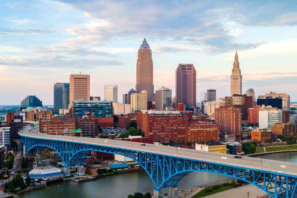 The blue steel arches of the Main Avenue Bridge over the Cuyahoga River in Cleveland, Ohio, with Key Tower and Terminal Tower rising in the downtown skyline behind it